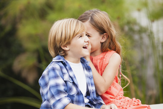 Girl whispering into boy's ear