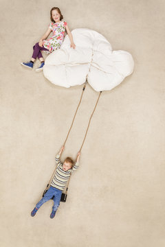 Children swinging on clouds