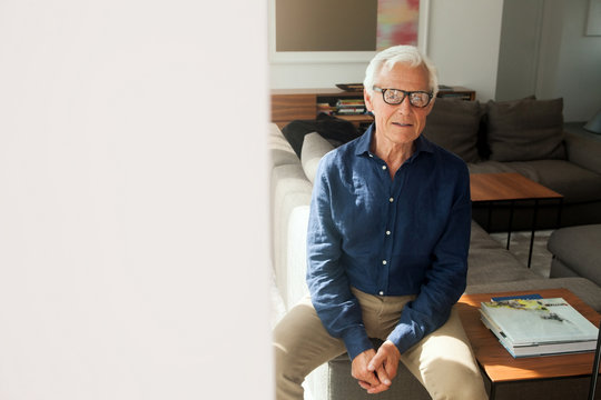 Portrait of senior man wearing glasses sitting in his living room