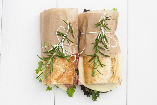 Baguette sandwiches with rosemary on white wood boards