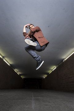 Young breakdancer jumping in the air in underpass