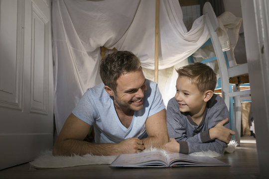 Father and son having fun in self-made tent at home
