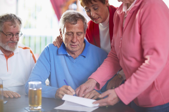 Senior man with friends signing document