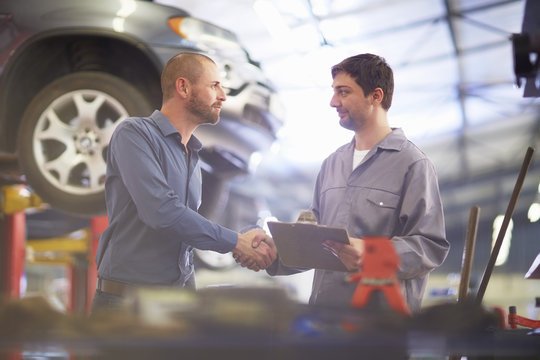 Car mechanic and client shaking hands in repair garage - Powered by Adobe