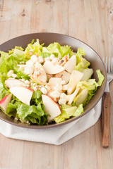 salad with apples and walnuts on rustic wooden background