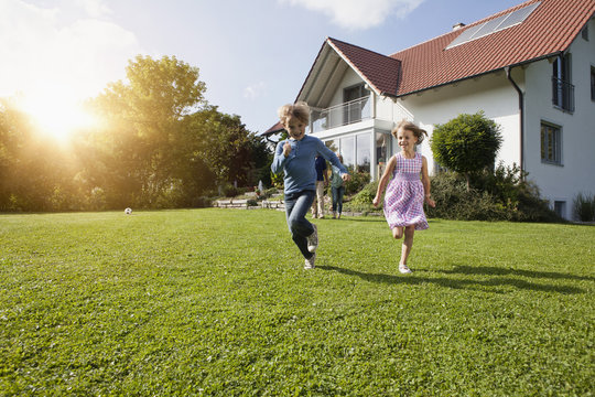 Fototapeta Brother and sister running in garden