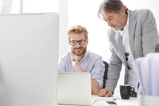 Two businessmen with laptop at desk