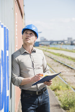 Portrait of man with blue safety helmet checking cargo containers