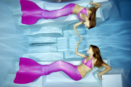 Mermaid girl watching her reflection under water