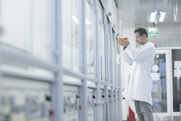 Chemist working in lab holding round bottom flask