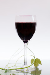 Red wine in glass with grape leaves
