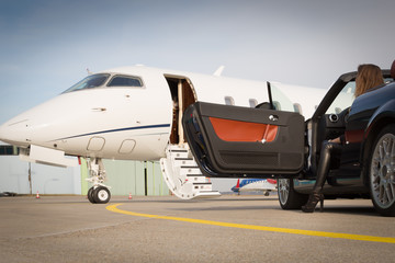woman convertible car and corporate private jet airplane - obrazy, fototapety, plakaty