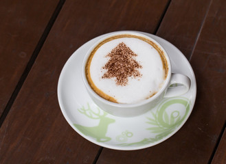 Coffee cup resting on a wooden table.