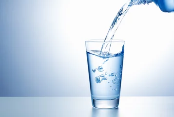 Selbstklebende Fototapete Wasser Wasser aus der Flasche ins Glas gießen