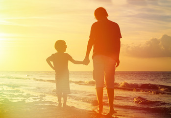 father and son holding hands at sunset