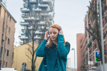 Fototapeta premium Beautiful girl listening to music in the city streets