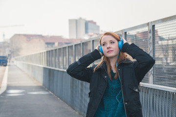 Beautiful girl with headphones posing in the city streets