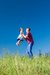 Outdoor portrait of a father who throws daughter in her arms