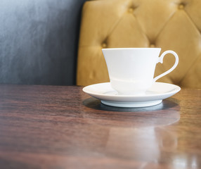Coffee cup on table in restaurant cafe with sofa background