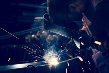 Employee at the factory welding steel using MIG MAG welder. - obrazy, fototapety, plakaty