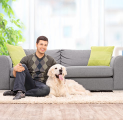 Young man sitting on the floor with his dog at home
