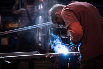 Employee at the factory welding steel using MIG MAG welder.