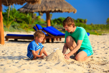 father and son building sand castle on the beach