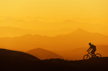 Fototapeta na wymiar biker riding on mountain silhouettes background