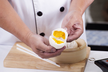 Hand of chefd holding steamed dumpling bun