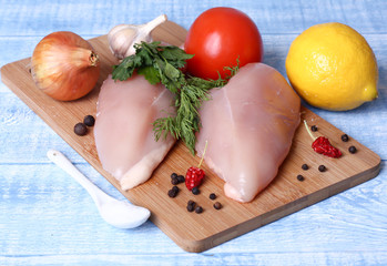 raw fillet chicken breast and vegetables on a cutting Board