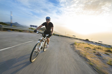 Fototapeta na wymiar Cyclist man riding mountain bike in sunny day on a mountain road