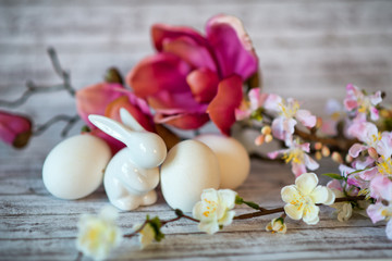 Fototapeta na wymiar Rabbit Figurine with White Eggs and Flowers