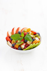 delicious fruit and berry salad in white bowl, vertical