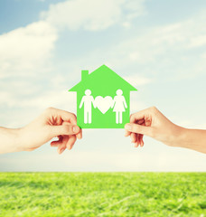 hands holding green house with family