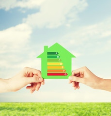 Naklejka premium hands holding green paper house