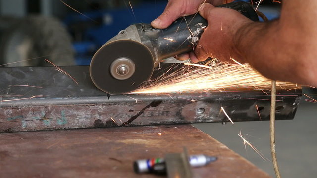 Worker doing using grinder during the process of adjusting metal for production