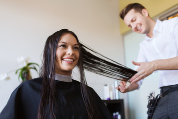 happy woman with stylist cutting hair at salon