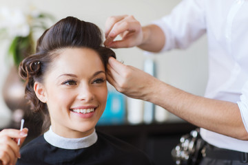 happy woman with stylist making hairdo at salon