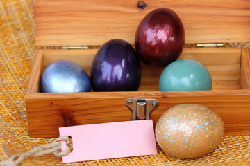 Colorful easter egg in wood box with paper tag.