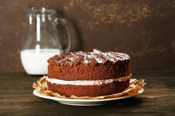 Delicious chocolate cake on table on brown background