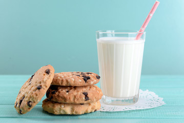 Tasty cookies and glass of milk on color wooden background