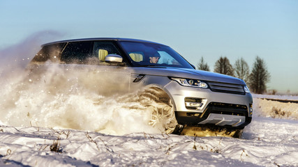 Powerful 4x4 offroader car running on snow field