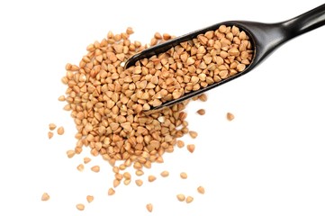 Raw green buckwheat in black wooden spoon, isolated