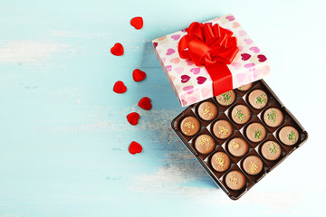 Gift box with tasty chocolate candies on wooden table
