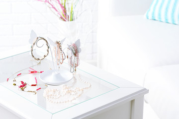 Decorative stand with jewelry and bijouterie on table in room
