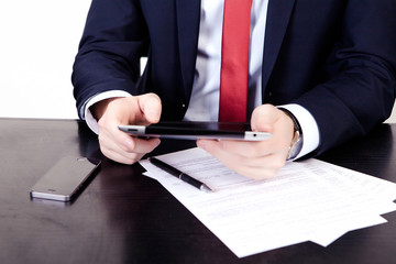 Businessman in red tie is looking to the plate. On the table is