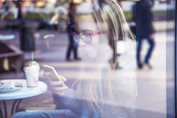 Young blonde girl texting message in cafe.