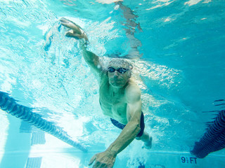 senior man swimming laps, underwater view