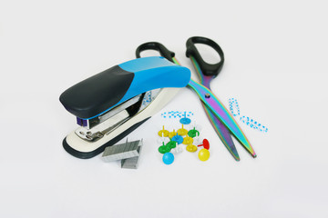 stapler, scissors, thumbtacks, paper clips on a light background