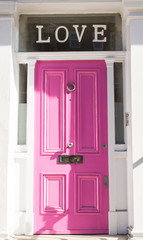 Jasnoróżowe drzwi na białej ścianie z napisem „Miłość” - 80036549
